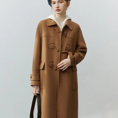 Warm camel wool coat with toggle closures and large front pockets, styled with a blue beret and white hoodie, perfect for winter fashion.