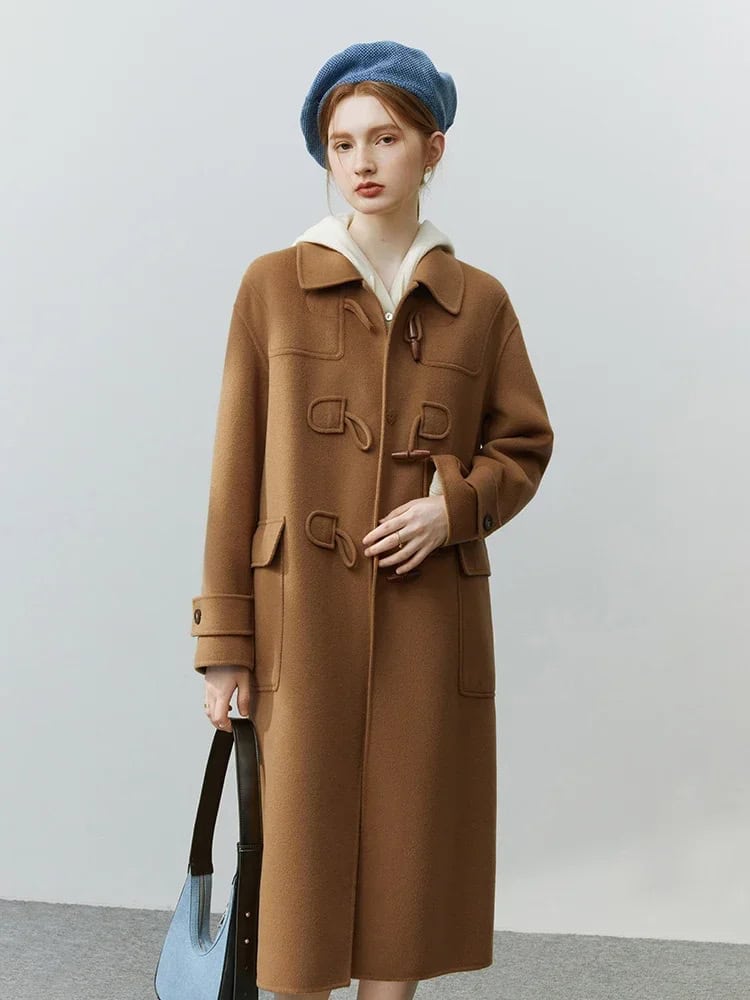 Warm camel wool coat with toggle closures and large front pockets, styled with a blue beret and white hoodie, perfect for winter fashion.