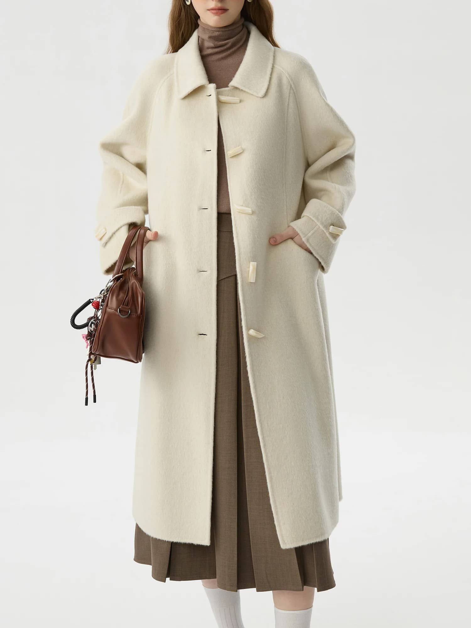 Elegant winter coat in cream wool with oversized collar, perfect for stylish cold-weather fashion. Features toggle buttons and side pockets, versatile and cozy for winter wear.