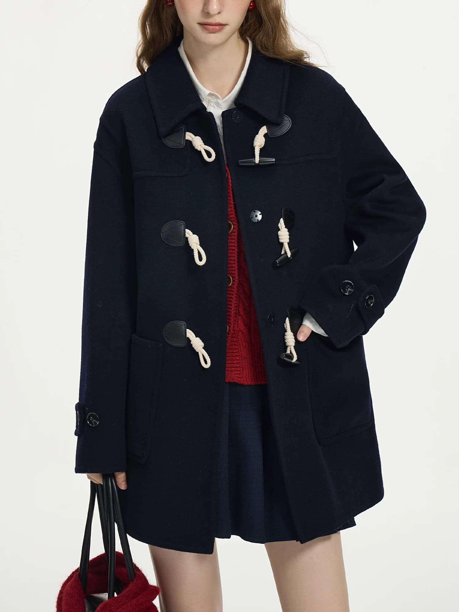 Cozy navy duffle coat with classic toggle closures, ideal for fall and winter fashion, paired with a red sweater and skirt for a stylish, warm look.