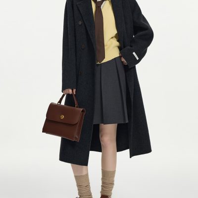 Stylish woman in fall fashion with oversized black coat, grey pleated skirt, mustard sweater, brown accessories, and leather shoes, showcasing trendy fall and winter wardrobe essentials at Monalisa Store.