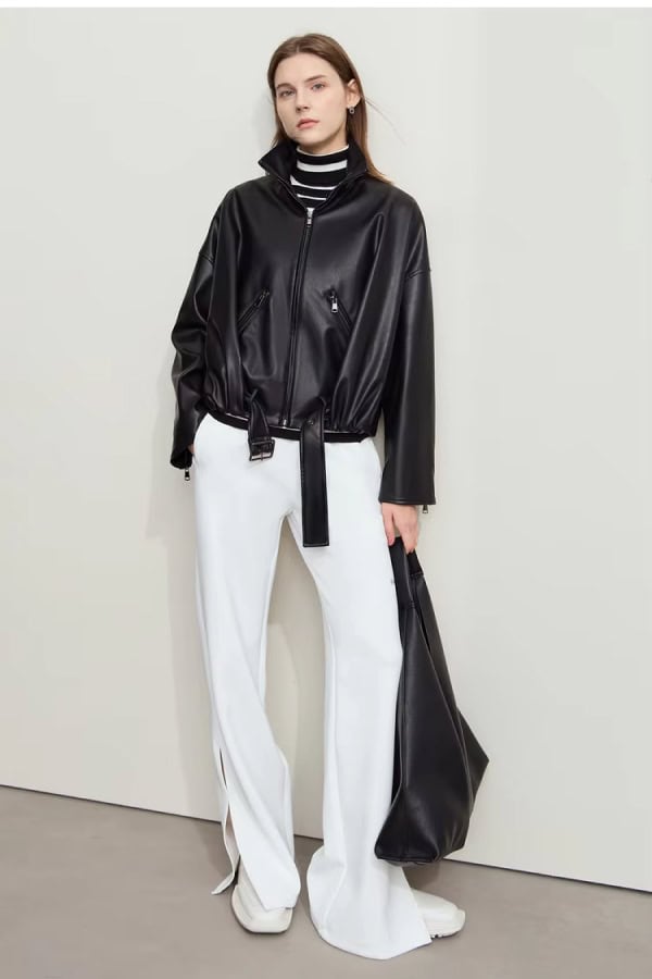Black faux leather jacket with zipper details and tie waist, paired with white wide-leg pants and stylish accessories, showcasing fashionable women's clothing at Monalisa Store.
