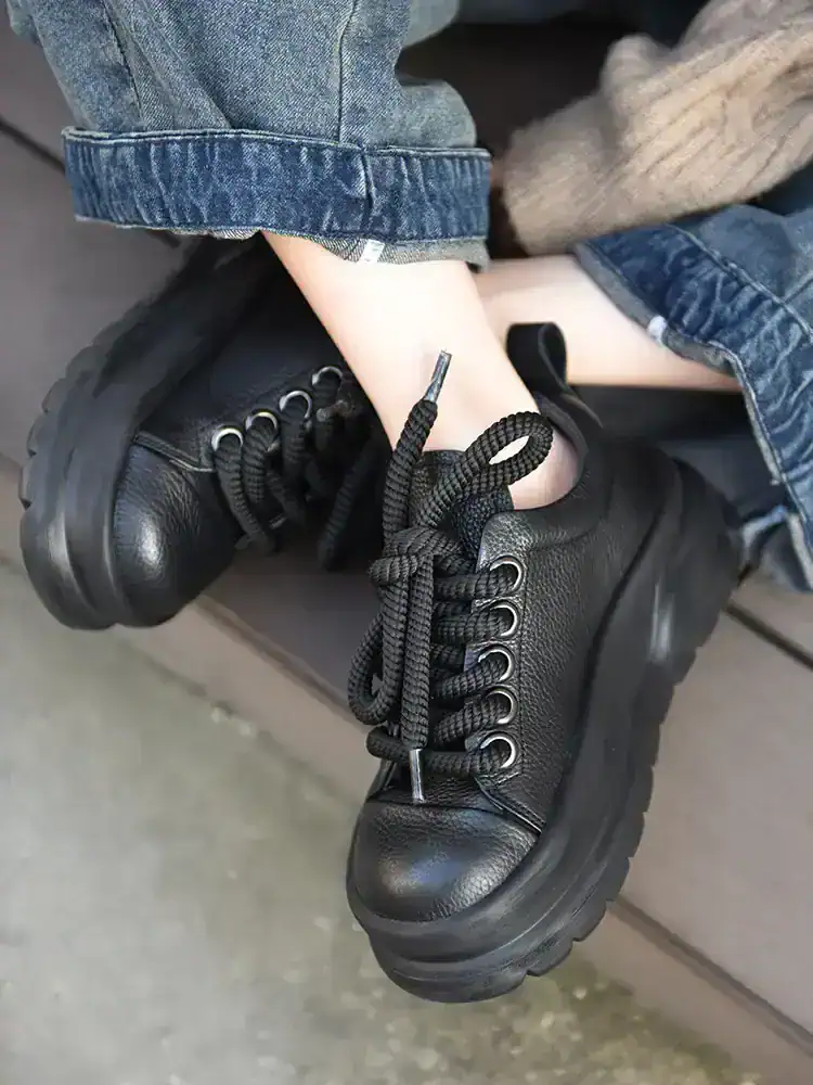 Black leather combat boots with thick soles and round toe, styled with rolled-up denim jeans, perfect for fashion-forward, comfortable footwear.