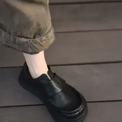 Black platform ankle boots with chunky soles, paired with rolled-up camouflage cargo pants, on dark wooden flooring. Perfect for stylish, comfortable footwear options from Monalisa Store.