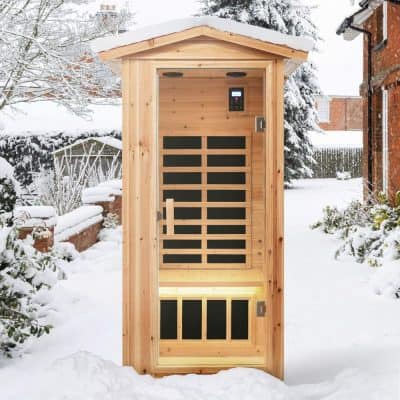 Compact outdoor sauna in a snowy garden, made of natural wood with modern black accents, perfect for relaxing and wellness in winter.