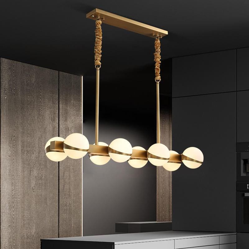 Modern chandelier with globe lights hanging over a contemporary kitchen island in a stylish home interior.