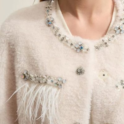 Elegant women's white coat embellished with sparkling rhinestones, pearls, and feather details for luxury fashion accessories.