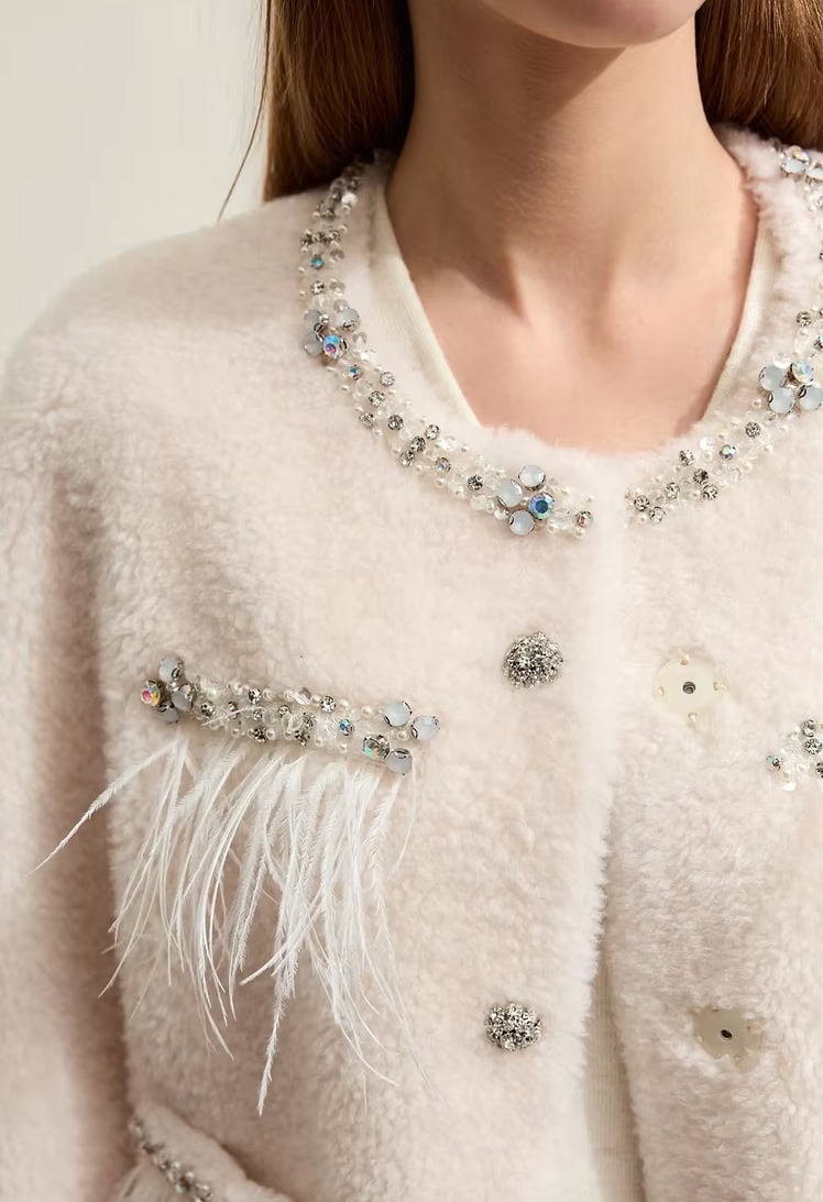Elegant women's white coat embellished with sparkling rhinestones, pearls, and feather details for luxury fashion accessories.