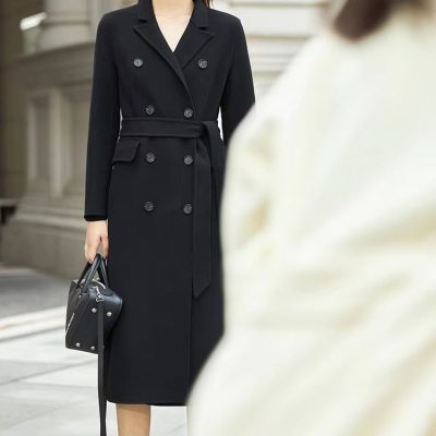 Stylish woman wearing a black trench coat, sunglasses, and carrying a black handbag, showcasing fashionable women’s outerwear from Monalisa Medical Store for modern urban style.