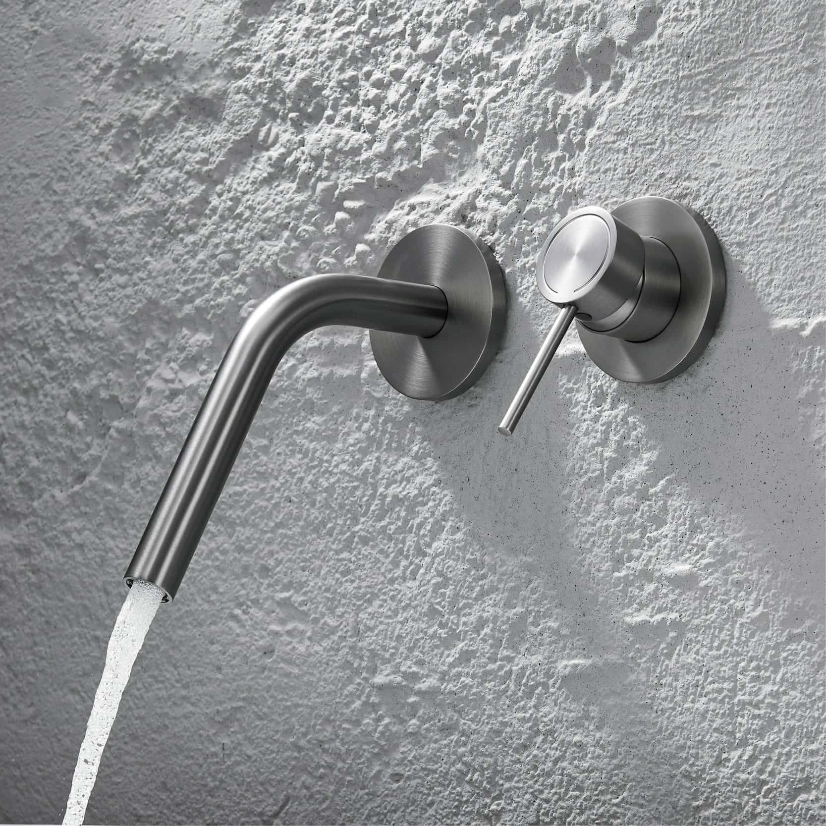 Sleek modern stainless steel wall-mounted faucet with water flowing, installed against textured white wall, ideal for contemporary bathroom or medical clinic settings.