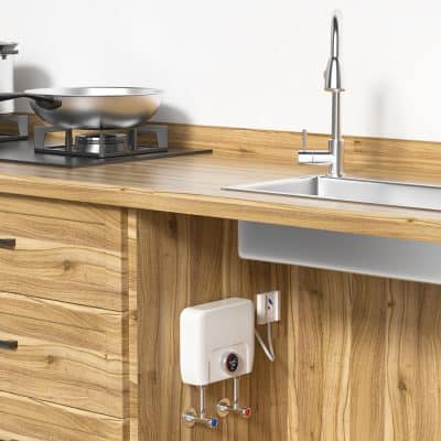 Stainless steel kitchen sink and gas stove on wooden countertop in modern kitchen setting.