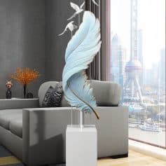 Blue feather sculpture with birds art decor in modern living room overlooking city skyline.