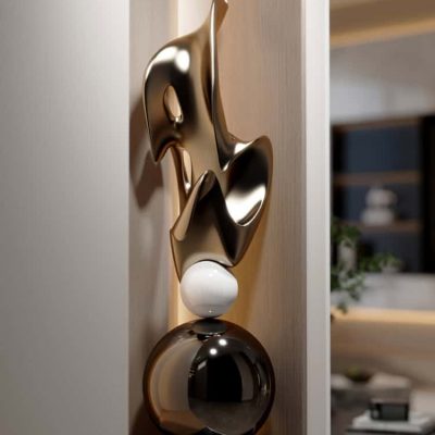 Sculptural modern art piece with metallic gold and black finishes, featuring abstract shapes and a white sphere, displayed in a contemporary interior setting.
