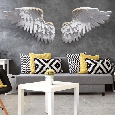 Elegant bedroom decor with white angel wings wall art, black and yellow patterned cushions, modern sofa, and minimalist white coffee table, emphasizing stylish interior design and home decoration ideas.