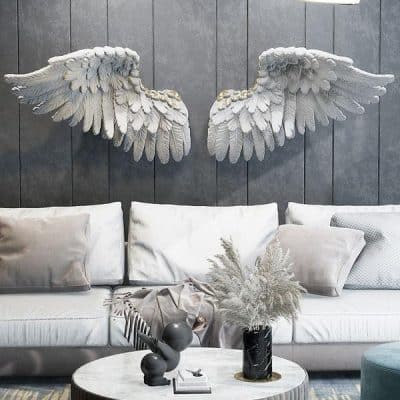 White angel wing wall art sculpture behind sofa in modern living room, decorative decor piece, Monalisa Store.