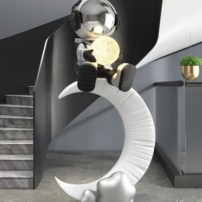 Cute astronaut figurine sitting on a crescent moon holding a glowing moon lamp, modern decor with neutral tones.