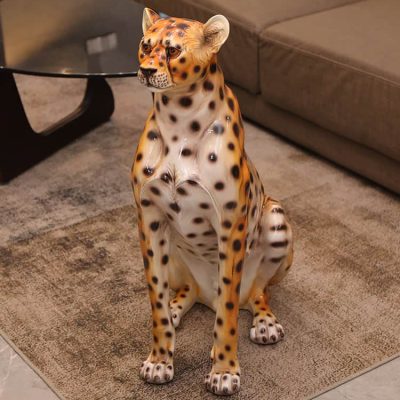 Realistic leopard sculpture sitting on a rug in a living room.