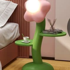 Flower-shaped LED lamp beside a bed with a green side table, modern bedroom decor, playful nightstand design, mood lighting for bedrooms, stylish bedroom accessories for a cozy ambiance.