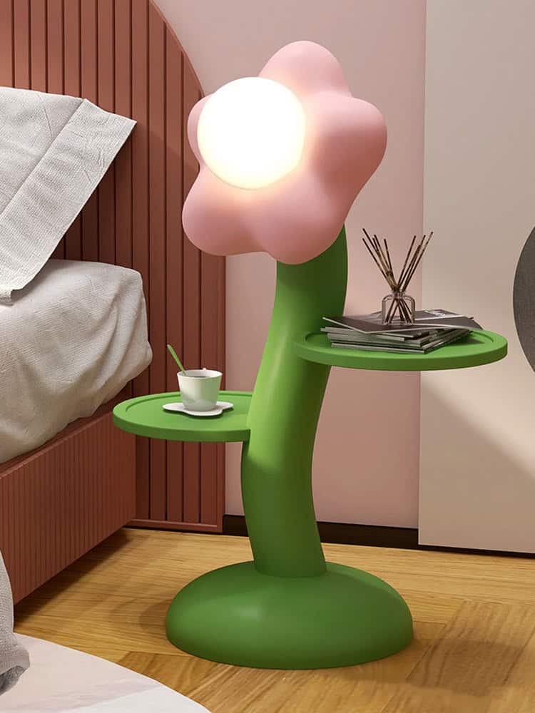 Flower-shaped LED lamp beside a bed with a green side table, modern bedroom decor, playful nightstand design, mood lighting for bedrooms, stylish bedroom accessories for a cozy ambiance.