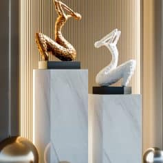 Elegant swan sculptures displayed on marble pedestal stands, featuring gold and white finishes, surrounded by decorative metallic spheres, showcasing luxurious decor at Monalisa Store for modern interiors.