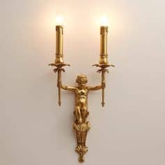 Antique gold wall sconce with a cherub figure holding two candle holders, elegant lighting fixture for luxury interior decor.