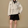 Modern beige women's outdoor jacket with hood, drawstrings, multiple pockets, and adjustable waist, suitable for casual and active wear. Perfect for protecting against wind and rain.