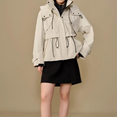 Modern beige women's outdoor jacket with hood, drawstrings, multiple pockets, and adjustable waist, suitable for casual and active wear. Perfect for protecting against wind and rain.