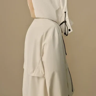 Light-colored medical jacket with hood, black drawstrings, and button details, designed for healthcare professionals, emphasizing comfort and style in medical settings.