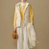 Comfy winter fashion outfit with a cozy beige puffer vest, yellow cardigan, white turtleneck, and wide-leg cream trousers, accessorized with a brown furry handbag and ivory scarf. Perfect for stylish cold-weather wear.