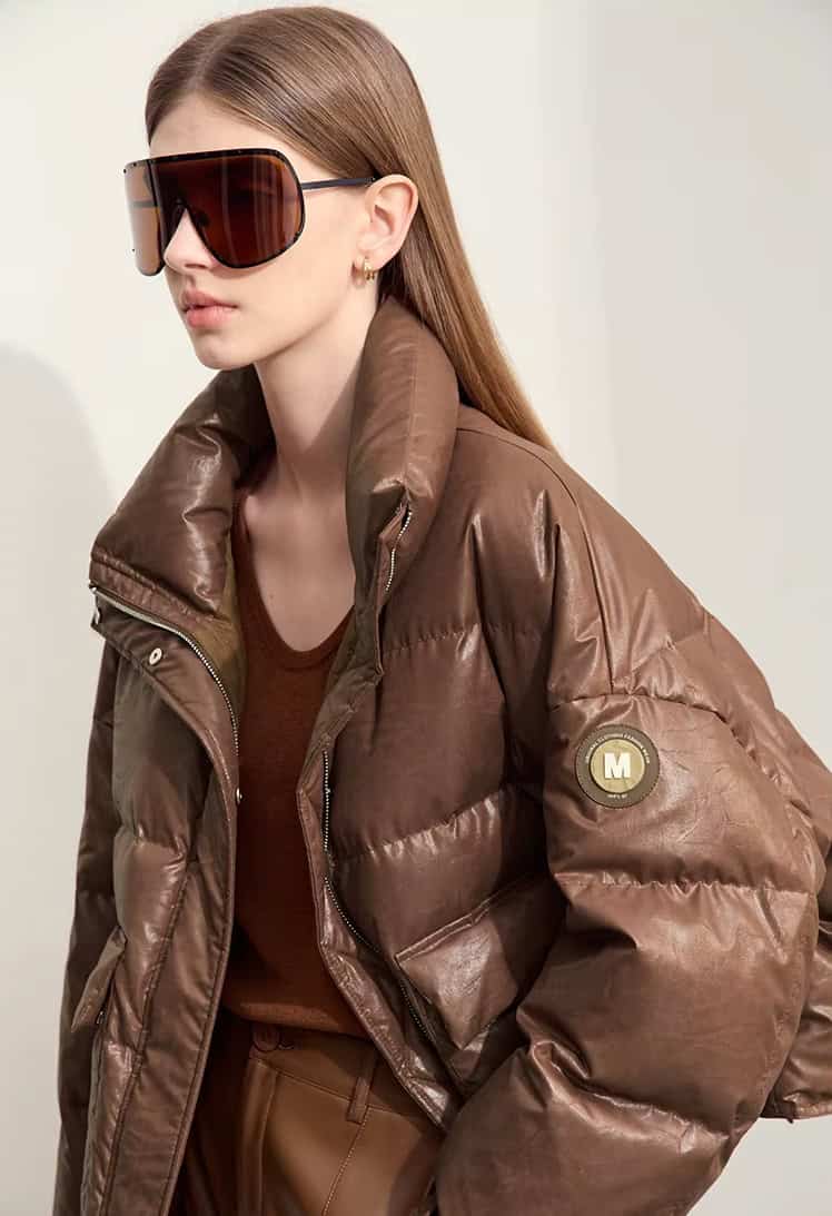 Oversized brown leather puffer jacket with logo patch, stylish sunglasses, and fashionable outfit on female model, perfect for luxury outerwear shopping at Monalisa Store.