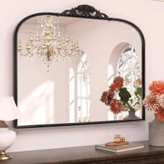 Luxurious decorative mirror with ornate black frame, elegant chandelier reflection, and stylish floral arrangement, perfect for enhancing interior decor in homes and living spaces.