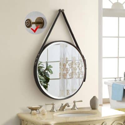 Vintage round mirror with leather strap, wall-mounted decor, bathroom vanity with elegant fixtures, and natural light in a bright, airy space.