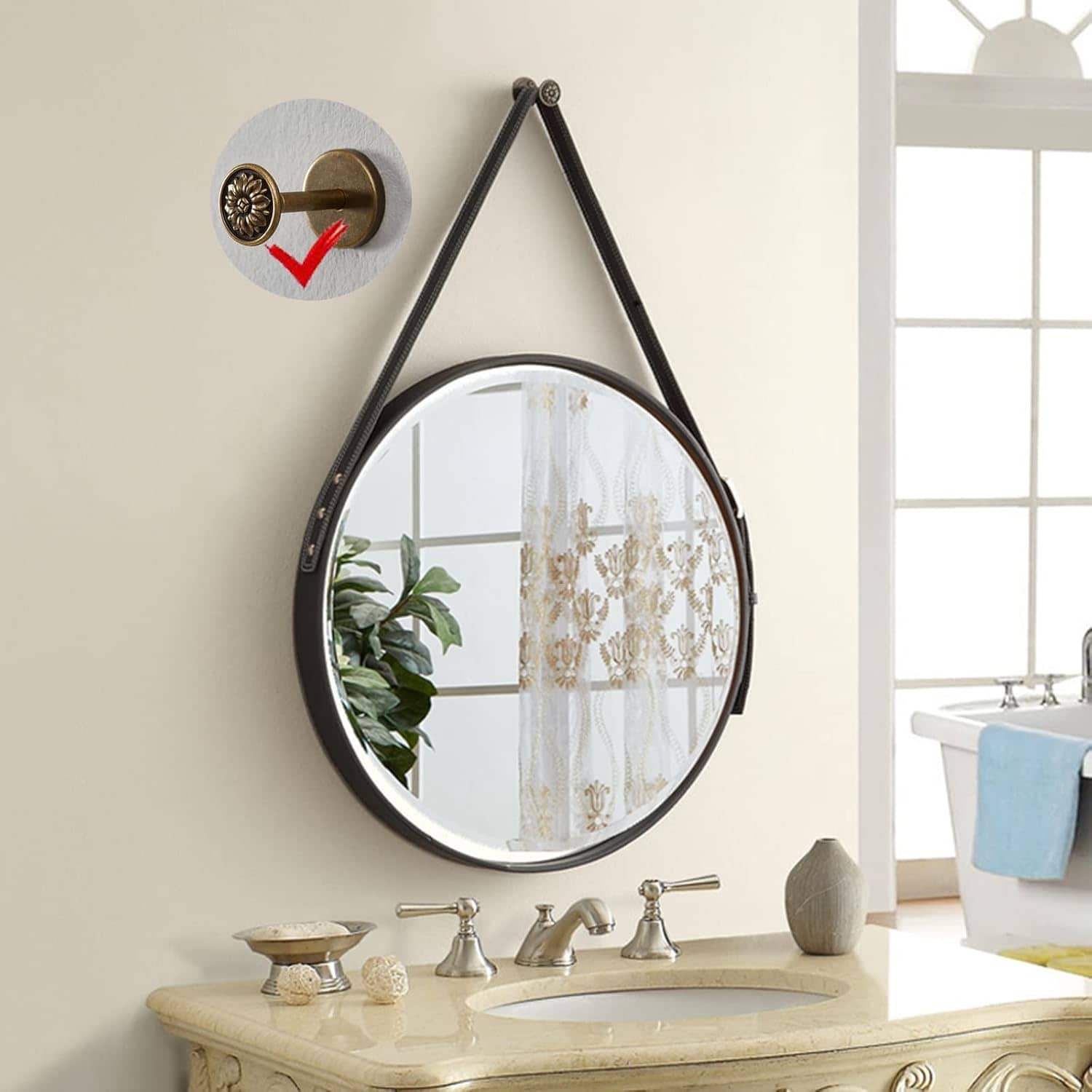 Vintage round mirror with leather strap, wall-mounted decor, bathroom vanity with elegant fixtures, and natural light in a bright, airy space.