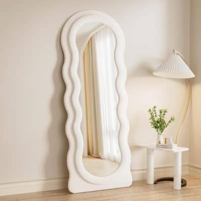 Wavy white full-length mirror with a modern, artistic frame in a contemporary bedroom decor.