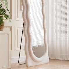 Wavy full-length mirror with a modern, sculptural frame reflecting natural light in a stylish interior space for elegant home decor.