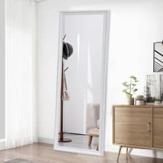 Elegant full-length white framed mirror in modern bedroom interior with hats and handbag on stand, natural light, minimalist decor, showcasing stylish and functional home essentials.