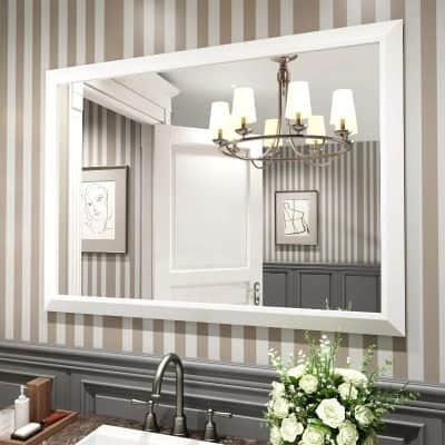 Mirror reflection of a chandelier hanging above a bathroom sink with a flower arrangement on the countertop, wall art in the background, and striped wallpaper in a stylish Monalisa Store interior design setting.