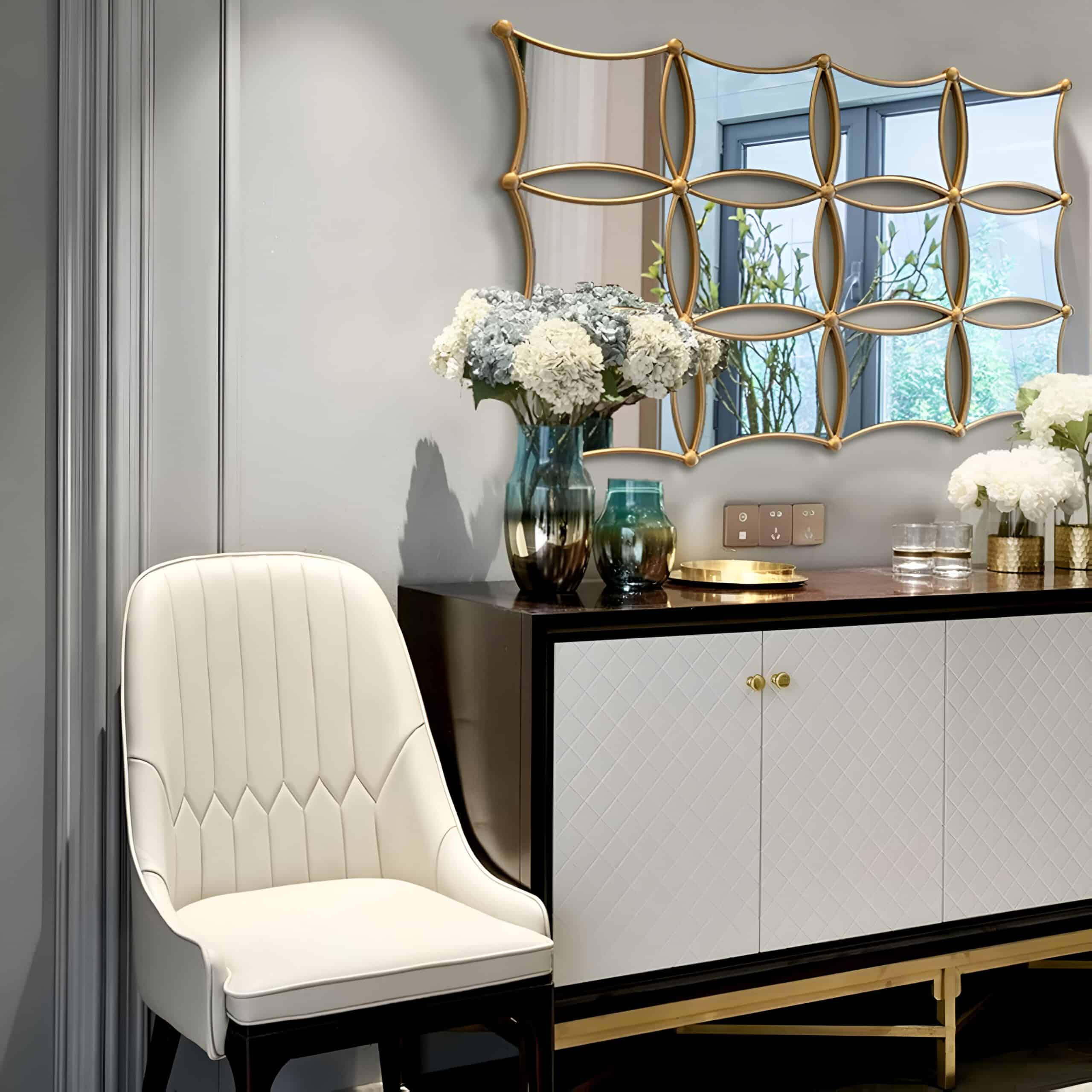Elegant interior with a modern white chair, stylish black and white sideboard, floral decor, and a decorative mirror, creating a luxurious ambiance perfect for an optometry or optical store setting.
