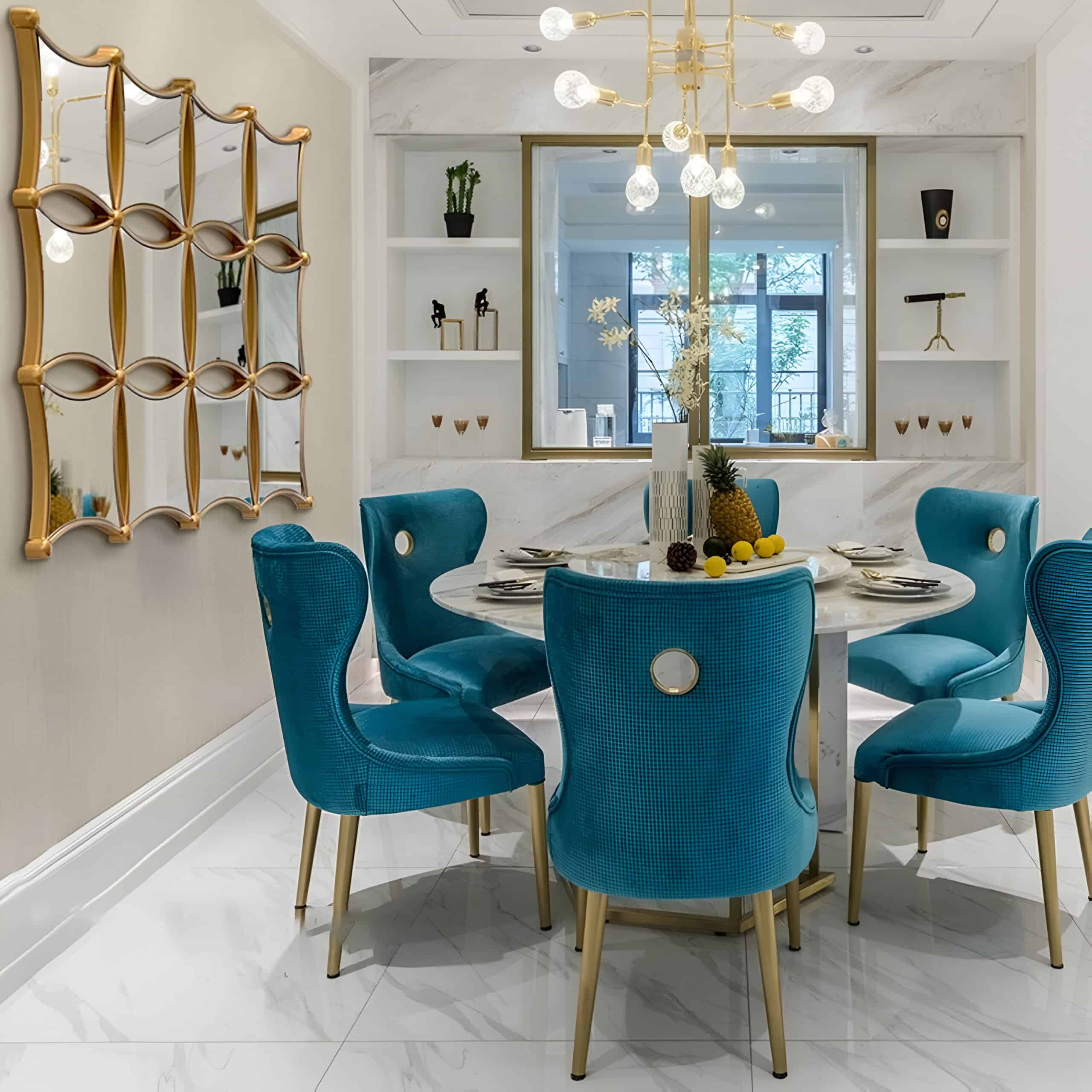 Blue upholstered dining chairs with gold accents surrounding a white marble table in a modern, elegant dining area at Monalisa Store.