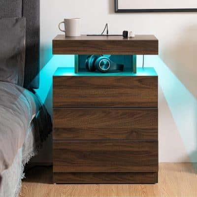 Modern wooden nightstand with built-in LED lighting, storing headphones and sitting next to a cozy bed in a stylish bedroom setup.