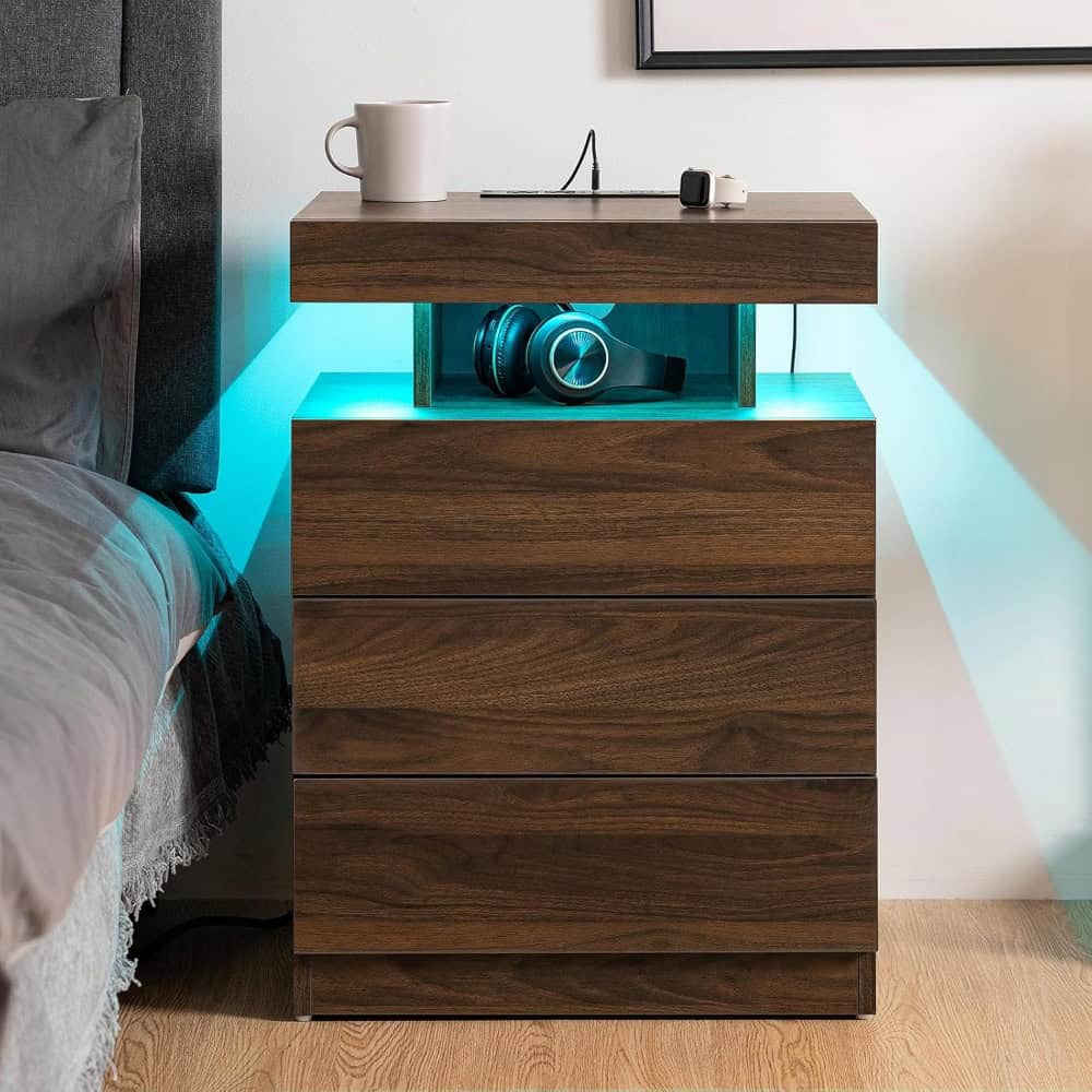 Modern wooden nightstand with built-in LED lighting, storing headphones and sitting next to a cozy bed in a stylish bedroom setup.