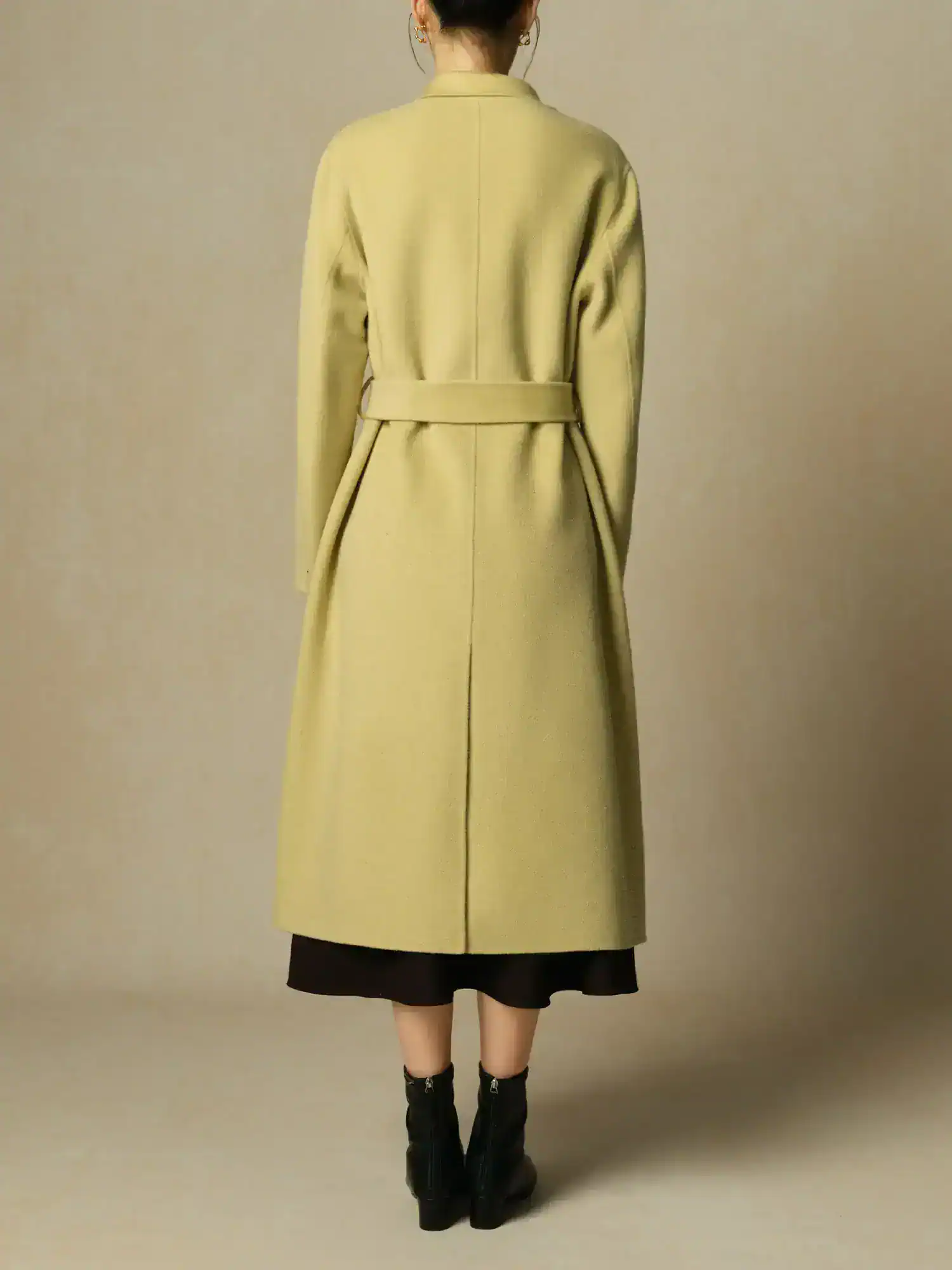 Elegant beige long coat with a belted waist, designed for women, featuring a stylish and luxurious look suitable for fashion-forward individuals. Perfect for fall and winter wear.