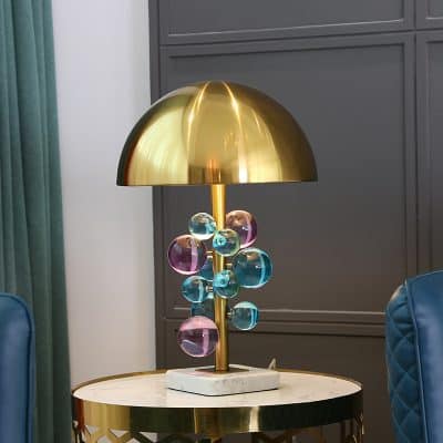 Shiny gold table lamp with colorful glass bubble accents on marble base, modern decorative lighting, luxurious home decor, stylish gold desk lamp, contemporary interior design element.