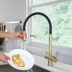 Modern black and gold kitchen faucet with pull-down sprayer, installed in a contemporary kitchen, providing stylish and functional water fixture for cooking and cleaning.