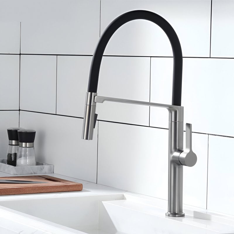 Brushed stainless steel kitchen faucet with black rubber hose and modern design, mounted on white tiled wall backdrop. Perfect for contemporary kitchen decor and water efficiency.