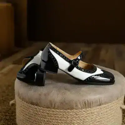 Black and white vintage-style Mary Jane shoes with decorative trim for women and girls stylishly displayed on a beige ottoman at Monalisa Store, perfect for elegant occasions.