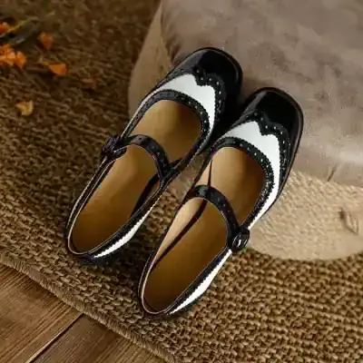 Black and white patent leather Mary Jane shoes with decorative stitching, ideal for stylish women’s footwear collections. Perfect for everyday wear or special occasions, combining elegance and comfort.