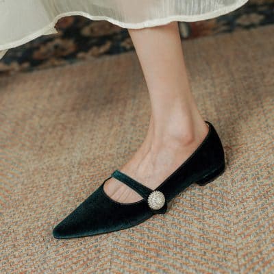 Black velvet pointed-toe flats with a decorative pearl button strap - elegant and comfortable footwear for women.