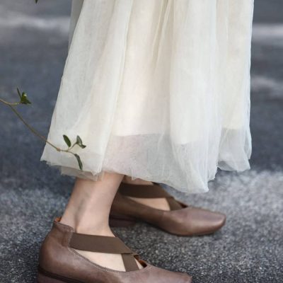 Comfy brown leather flats on woman's feet with flowing white dress, outdoor fashion footwear, stylish casual shoes, Monalisa Medical store products.