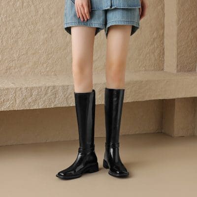 Sleek black knee-high rain boots paired with denim shorts, perfect for stylish rainy day footwear. Stylish, waterproof, and comfortable for women’s fashion needs.